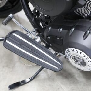 A motorcycle is parked in the garage with its pedals.