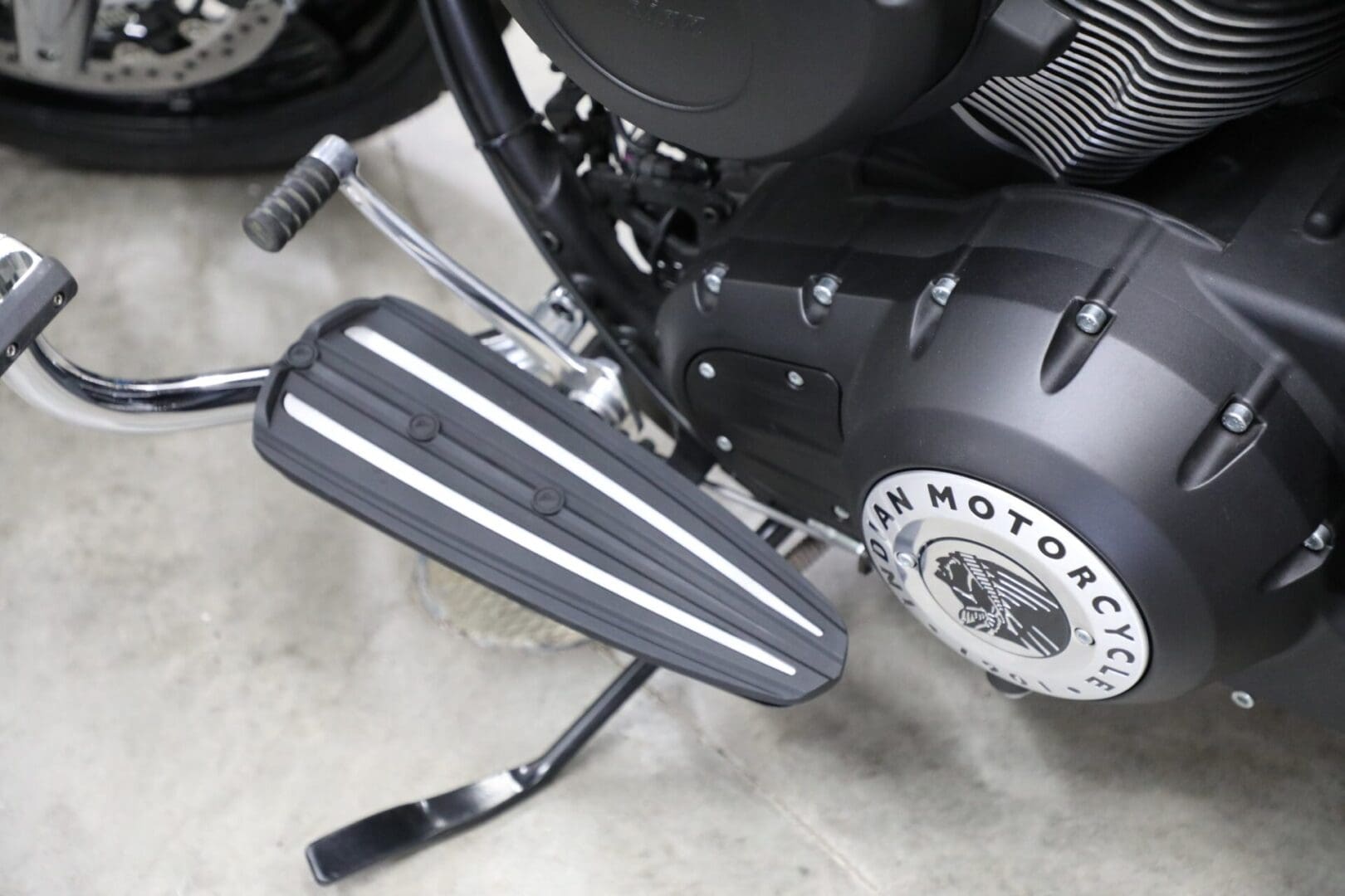 A motorcycle is parked in the garage with its pedals.